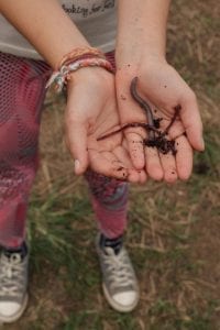 Menina mostra minhocas que vivem em pátio de compostagem. Foto: Cris Fontinha